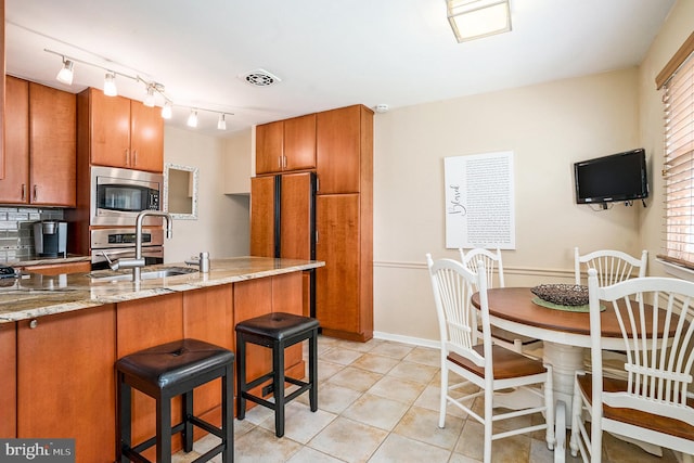 1057 Fitzwatertown Rd, Roslyn, PA 19001 - kitchen featuring stainless steel microwave, a kitchen breakfast bar, visible vents, brown cabinets, and a sink
