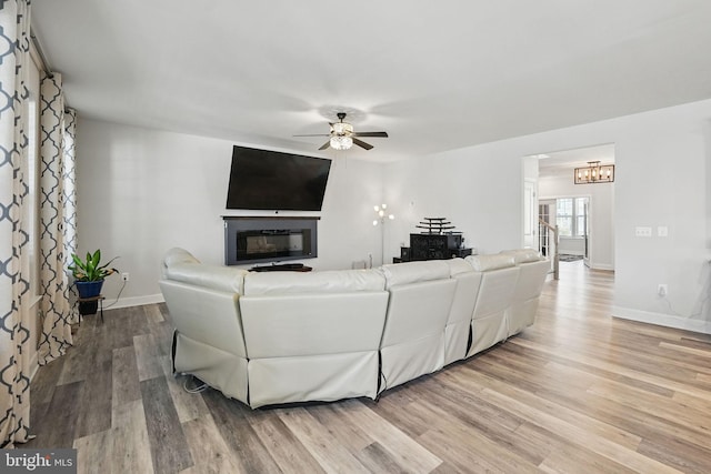 131 Boxelder Dr, Stafford, VA 22554 - living area featuring light wood finished floors, baseboards, a glass covered fireplace, and ceiling fan with notable chandelier