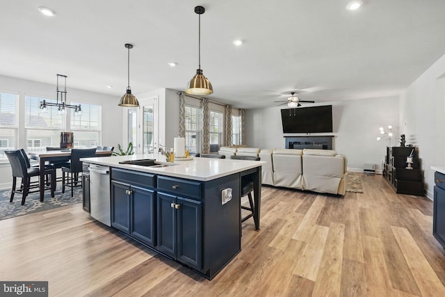131 Boxelder Dr, Stafford, VA 22554 - kitchen with stainless steel dishwasher, blue cabinetry, light wood-style floors, ceiling fan with notable chandelier, and a sink