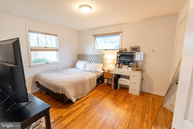 bedroom with baseboards, light wood finished floors, and multiple windows