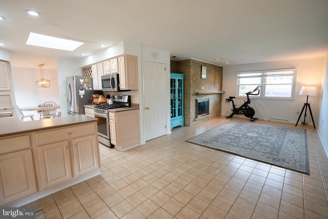 kitchen with a skylight, appliances with stainless steel finishes, a brick fireplace, open floor plan, and light tile patterned flooring