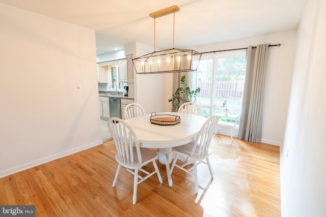 dining space with baseboards, light wood finished floors, and a notable chandelier