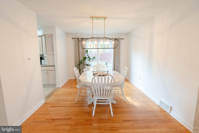 dining space with a notable chandelier, visible vents, baseboards, and light wood-type flooring