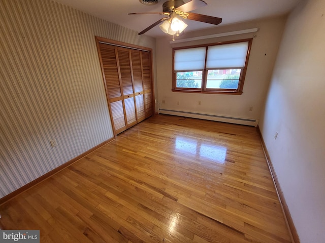 212 University Dr, Mont Alto, PA 17237 - unfurnished bedroom with a closet, a baseboard radiator, baseboards, wallpapered walls, and wood finished floors