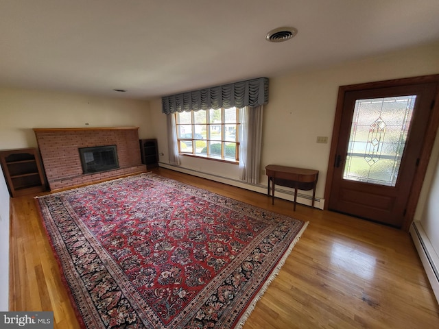 212 University Dr, Mont Alto, PA 17237 - living room with a brick fireplace, visible vents, a baseboard heating unit, and light wood-type flooring