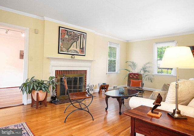 living room with light wood-style floors, crown molding, a brick fireplace, and baseboards
