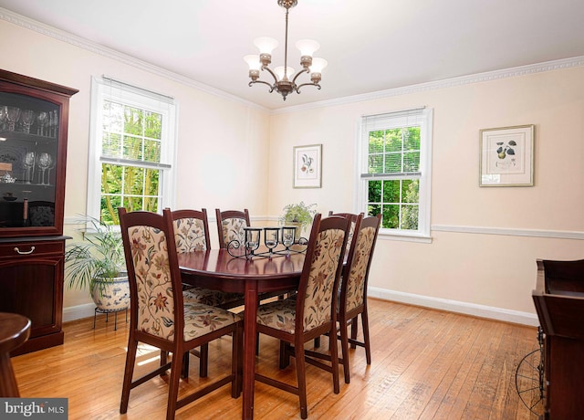 dining room featuring light wood finished floors, a chandelier, ornamental molding, and baseboards