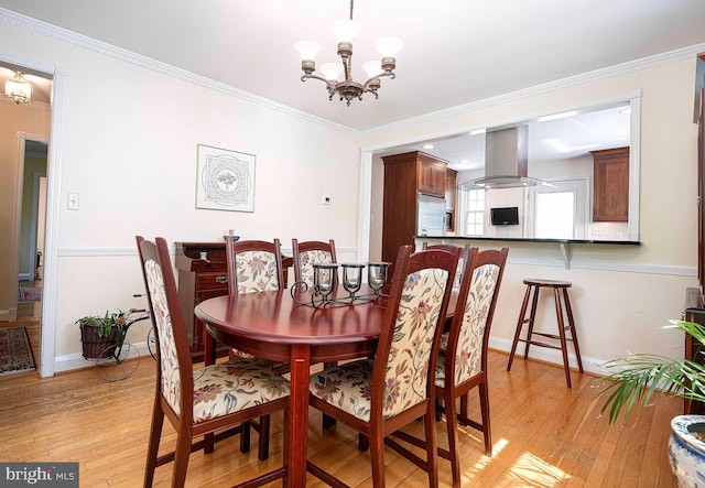 dining space with a chandelier, light wood finished floors, baseboards, and crown molding