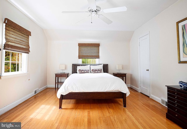 bedroom featuring light wood finished floors, baseboards, lofted ceiling, and a ceiling fan