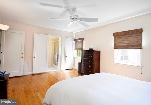 bedroom featuring light wood-style floors, ceiling fan, ensuite bathroom, and baseboards