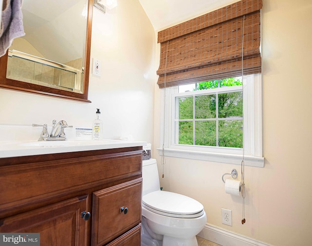 bathroom with toilet, vanity, a shower with shower door, baseboards, and tile patterned flooring