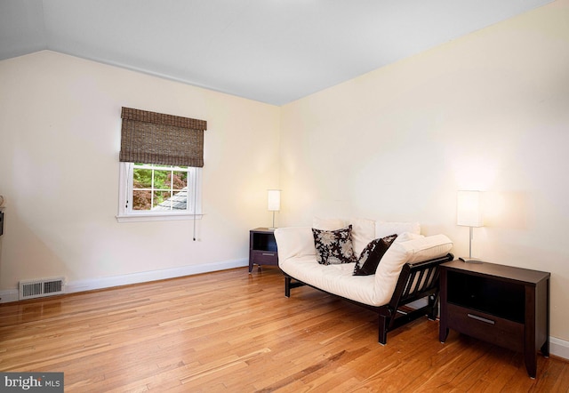 living area featuring wood-type flooring, vaulted ceiling, and baseboards