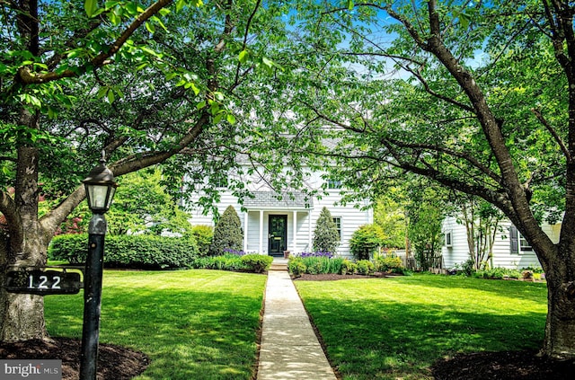 view of property hidden behind natural elements featuring a front yard