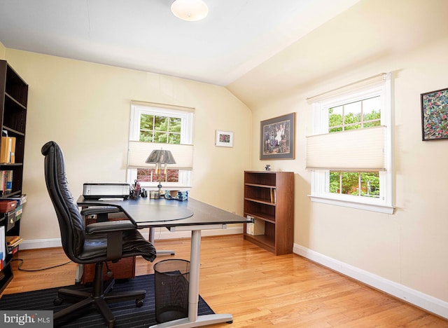 office space with light wood-style floors, baseboards, and lofted ceiling