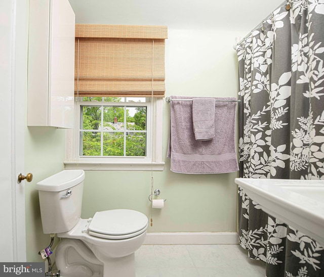 full bathroom with toilet, baseboards, and marble look tiles