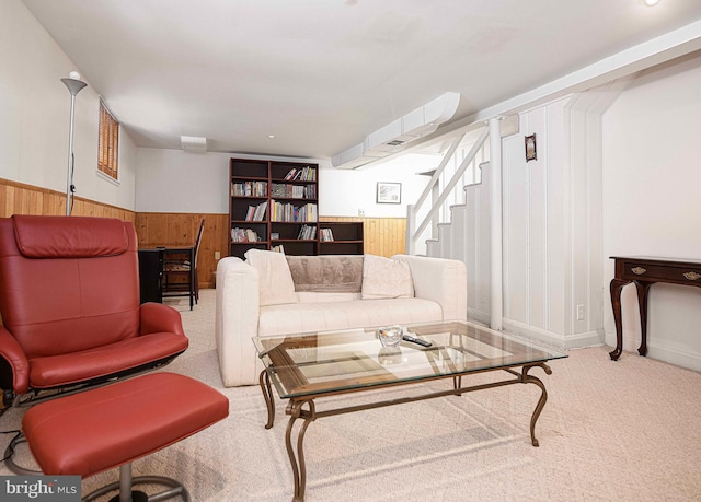 living room featuring carpet floors, a wainscoted wall, wood walls, and stairs