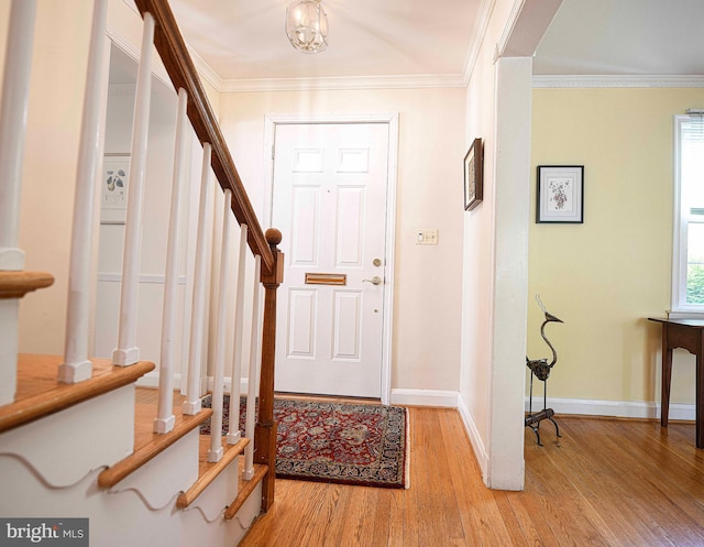entrance foyer featuring light wood finished floors, baseboards, stairway, and crown molding