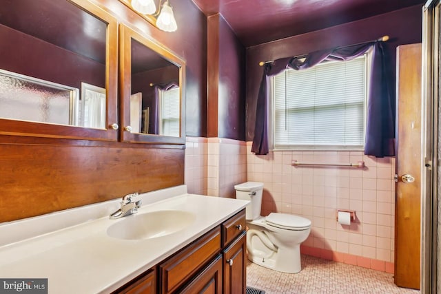 bathroom with toilet, tile patterned floors, tile walls, and vanity