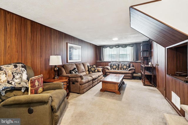 carpeted living room with visible vents and wood walls