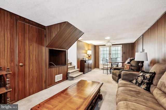 living room with light carpet, stairs, a textured ceiling, and visible vents