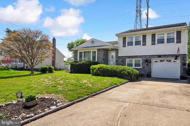 tri-level home featuring fence, a front yard, stone siding, an attached garage, and driveway