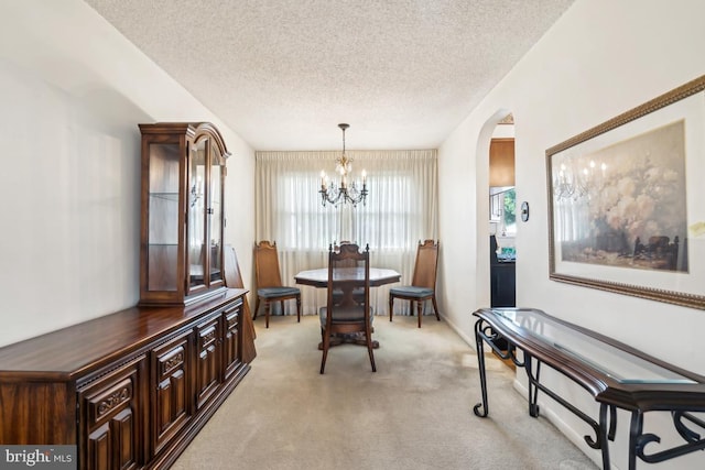 dining area with arched walkways, a textured ceiling, a chandelier, and light carpet