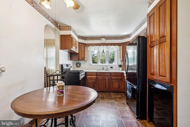 kitchen featuring a sink, stainless steel range with gas stovetop, freestanding refrigerator, wine cooler, and stone tile flooring