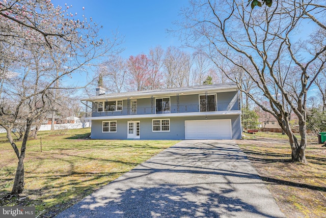 view of front of property with driveway, french doors, an attached garage, a balcony, and a front lawn
