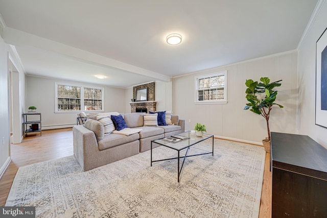 living room featuring baseboards, ornamental molding, wood finished floors, and a brick fireplace