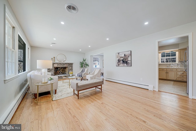 living room featuring a baseboard radiator, light wood-style floors, and visible vents