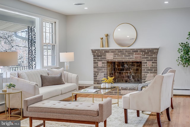 living room featuring recessed lighting, baseboard heating, visible vents, a fireplace, and wood finished floors