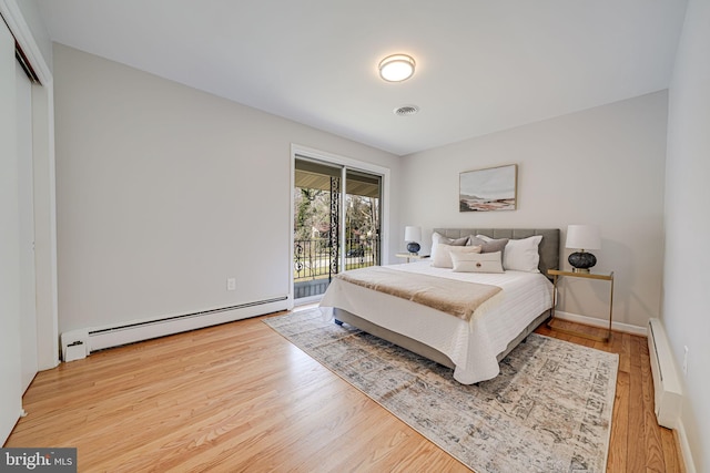 bedroom with visible vents, a baseboard radiator, wood finished floors, baseboard heating, and access to exterior