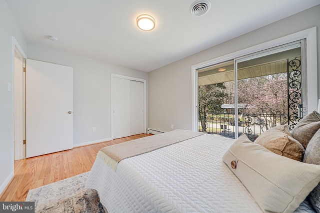 bedroom featuring baseboard heating, baseboards, access to exterior, visible vents, and wood finished floors