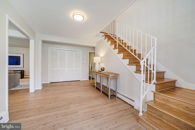 foyer entrance with baseboards, stairs, wood finished floors, and a baseboard radiator