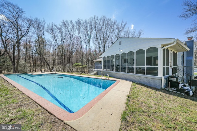 outdoor pool with a sunroom and a yard