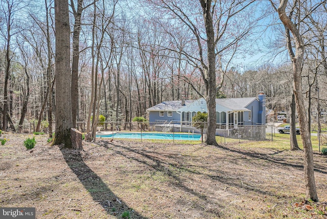 view of yard featuring an outdoor pool, a forest view, and fence