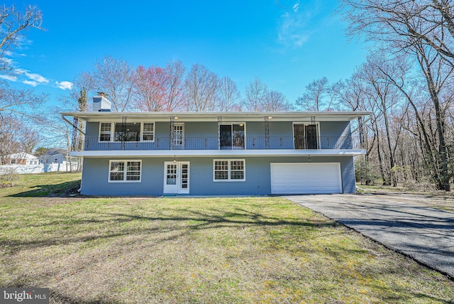 view of front of house featuring driveway, a front yard, a chimney, a balcony, and a garage