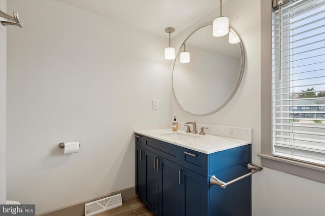 bathroom featuring toilet, vanity, wood finished floors, and visible vents