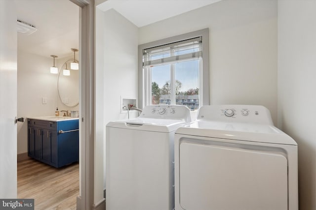 laundry room featuring laundry area, light wood finished floors, washer and dryer, and a sink