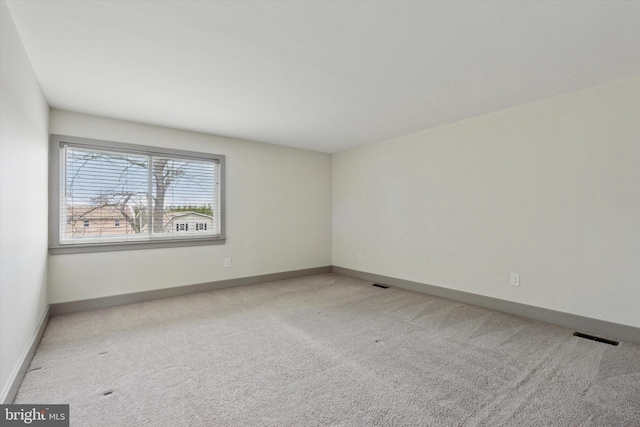 spare room with baseboards, carpet flooring, and visible vents