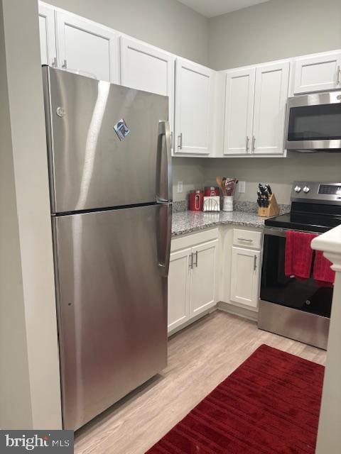 30609 Cedar Neck Rd Unit 3109, Ocean View, DE 19970 - kitchen featuring white cabinetry, light wood-style flooring, light stone countertops, and appliances with stainless steel finishes