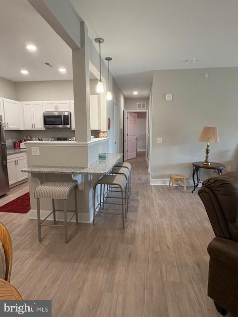 30609 Cedar Neck Rd Unit 3109, Ocean View, DE 19970 - kitchen with open floor plan, wood finished floors, a kitchen breakfast bar, and appliances with stainless steel finishes