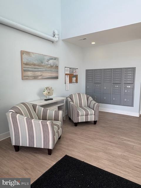 30609 Cedar Neck Rd Unit 3109, Ocean View, DE 19970 - sitting room featuring baseboards, a towering ceiling, wood finished floors, and mail area