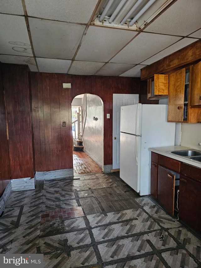 246 S Logan Ave, Trenton, NJ 08629 - kitchen with arched walkways, wood walls, a paneled ceiling, light countertops, and freestanding refrigerator