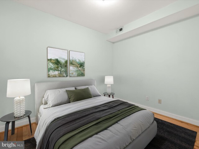 bedroom with baseboards, visible vents, and wood finished floors