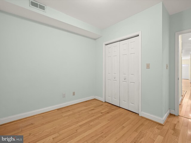 unfurnished bedroom with baseboards, visible vents, a closet, and light wood-style floors