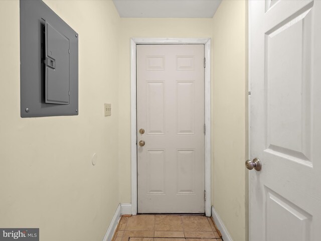 doorway to outside with light tile patterned flooring, baseboards, and electric panel