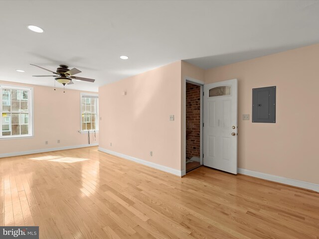 unfurnished room with electric panel, light wood-style flooring, baseboards, ceiling fan, and recessed lighting