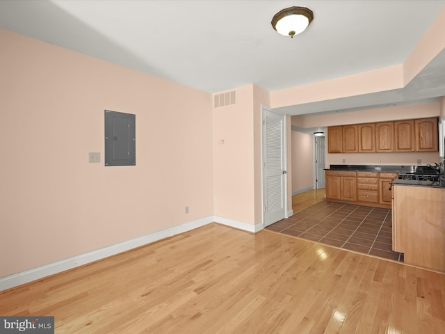kitchen with visible vents, electric panel, baseboards, a sink, and light wood-type flooring