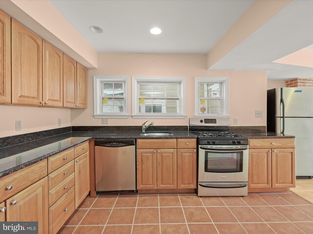 kitchen with dark stone counters, light tile patterned floors, a sink, and appliances with stainless steel finishes